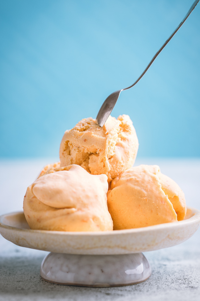 Peach Vegan ice cream in a white dish - At Your Table